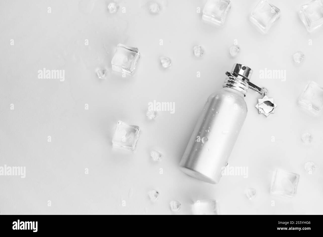 Bottiglia argentata di profumo femminile, Fotografia obiettivo di bottiglia di profumo metallico in cubetti di ghiaccio e acqua su tavola bianca. Vista dall'alto. Prodotto mockup Foto Stock