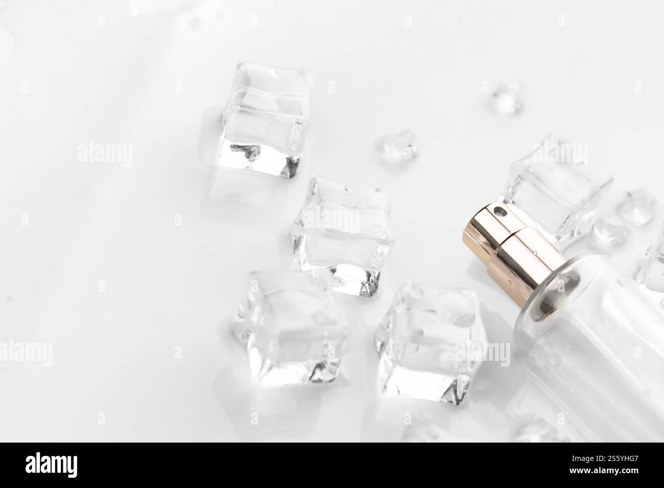 Bottiglia di profumo femminile, fotografia oggettiva della bottiglia di profumo in cubetti di ghiaccio e acqua. vista dall'alto. foto del prodotto, concetto di freschezza e aroma. Foto Stock