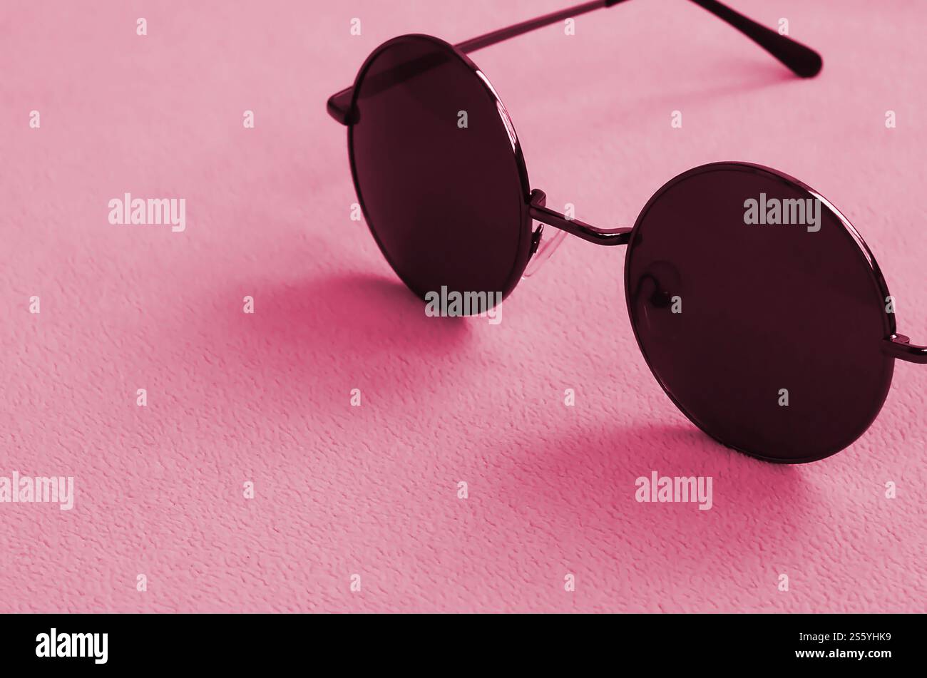 Gli eleganti occhiali da sole neri con occhiali rotondi si appoggiano su una coperta realizzata in morbido e soffice tessuto in pile. Immagine di sfondo alla moda. Tonalità immagine in Foto Stock