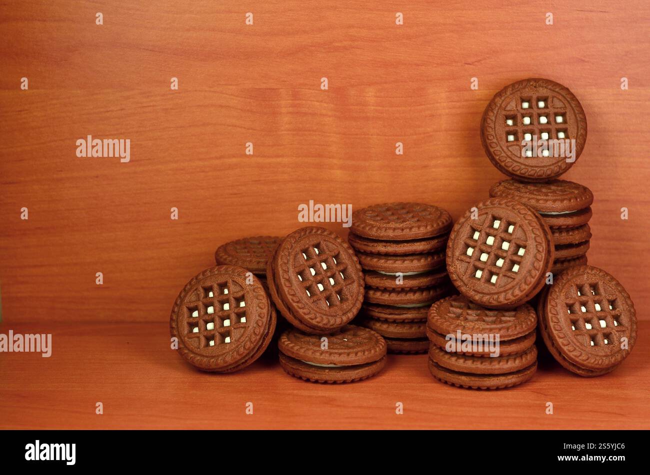 Panino al cioccolato, biscotti rotondi con ripieno di crema alla vaniglia su un tavolo di legno marrone con copyspace. Natura morta di biscotti dolci e gustosi con bianco Foto Stock