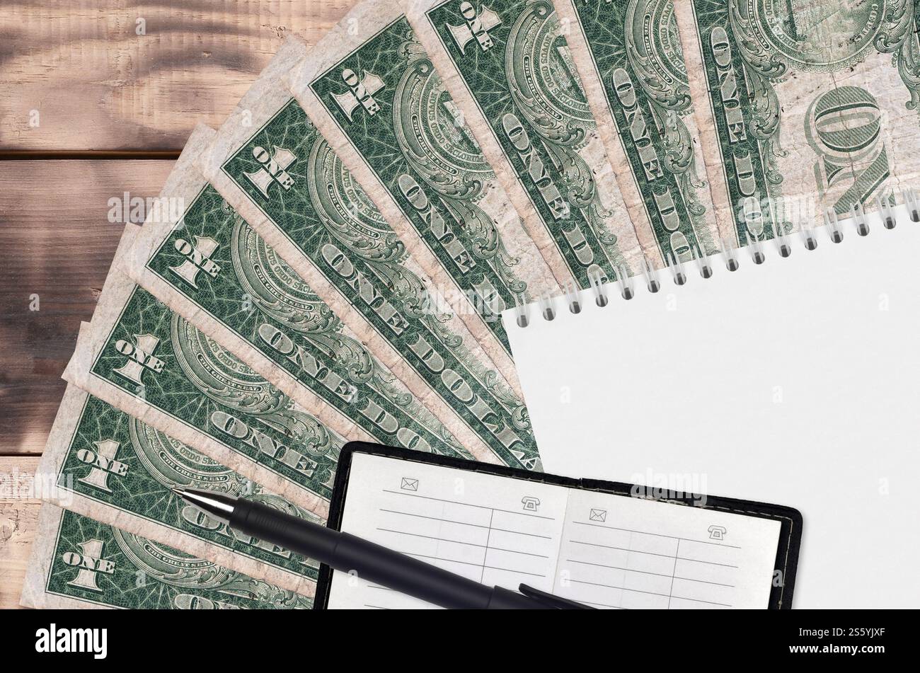 1 dollaro USA di banconote, ventola e blocco note con rubrica e penna nera. Concetto di pianificazione finanziaria e strategia aziendale. Contabilità e investimenti. 1 Foto Stock