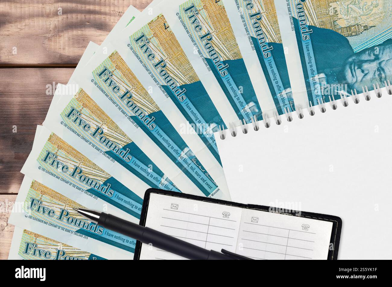 Ventola e blocco note da 5 sterline inglesi con rubrica e penna nera. Concetto di pianificazione finanziaria e strategia aziendale. Contabilità e. Foto Stock
