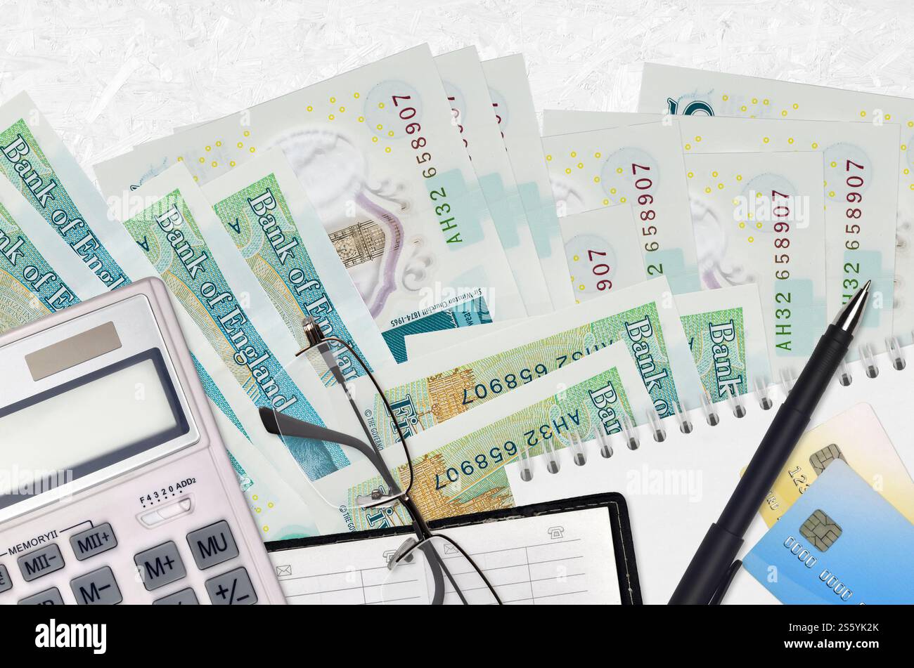 Banconote da 5 sterline inglesi e calcolatrice con occhiali e penna. Concetto di stagione del pagamento delle imposte o soluzioni di investimento. Pianificazione finanziaria o contabile Foto Stock