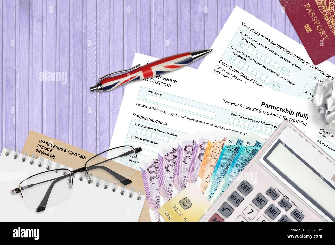 Modulo fiscale inglese sa104 Partnership di HM revenue and Customs si trova sul tavolo con gli articoli per ufficio. Documentazione HMRC e processo di pagamento delle tasse in United Foto Stock
