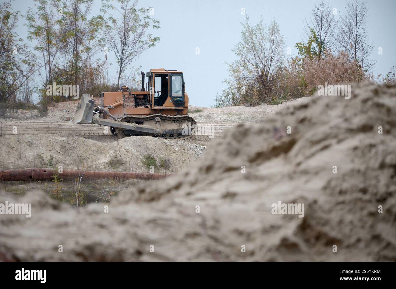 Aggregato da cava con macchinari per impieghi gravosi nel settore delle costruzioni. Escavatore pala Caterpillar con retroescavatore per la cava del cantiere. Foto Stock