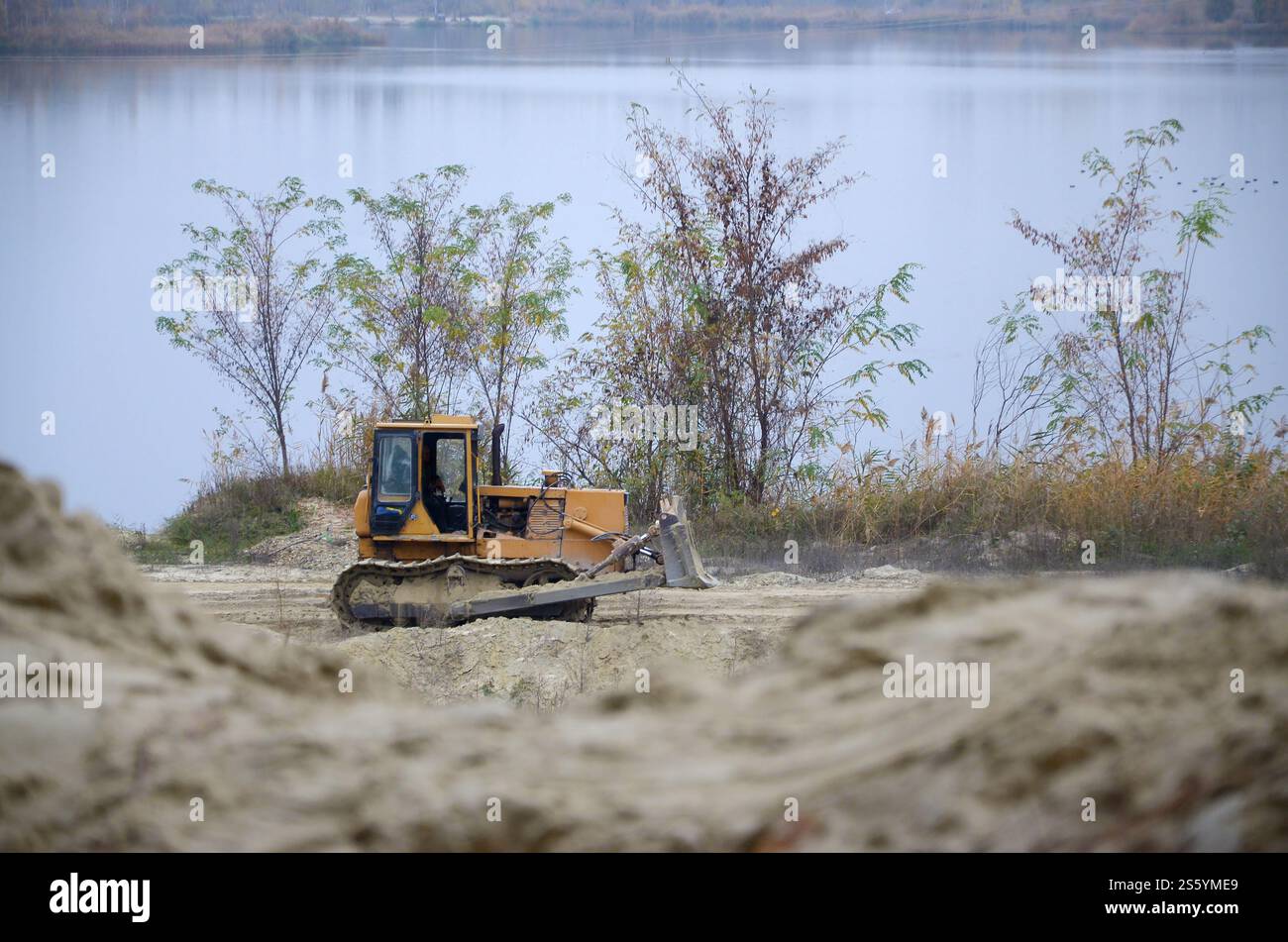Aggregato da cava con macchinari per impieghi gravosi nel settore delle costruzioni. Escavatore pala Caterpillar con retroescavatore per la cava del cantiere. Foto Stock