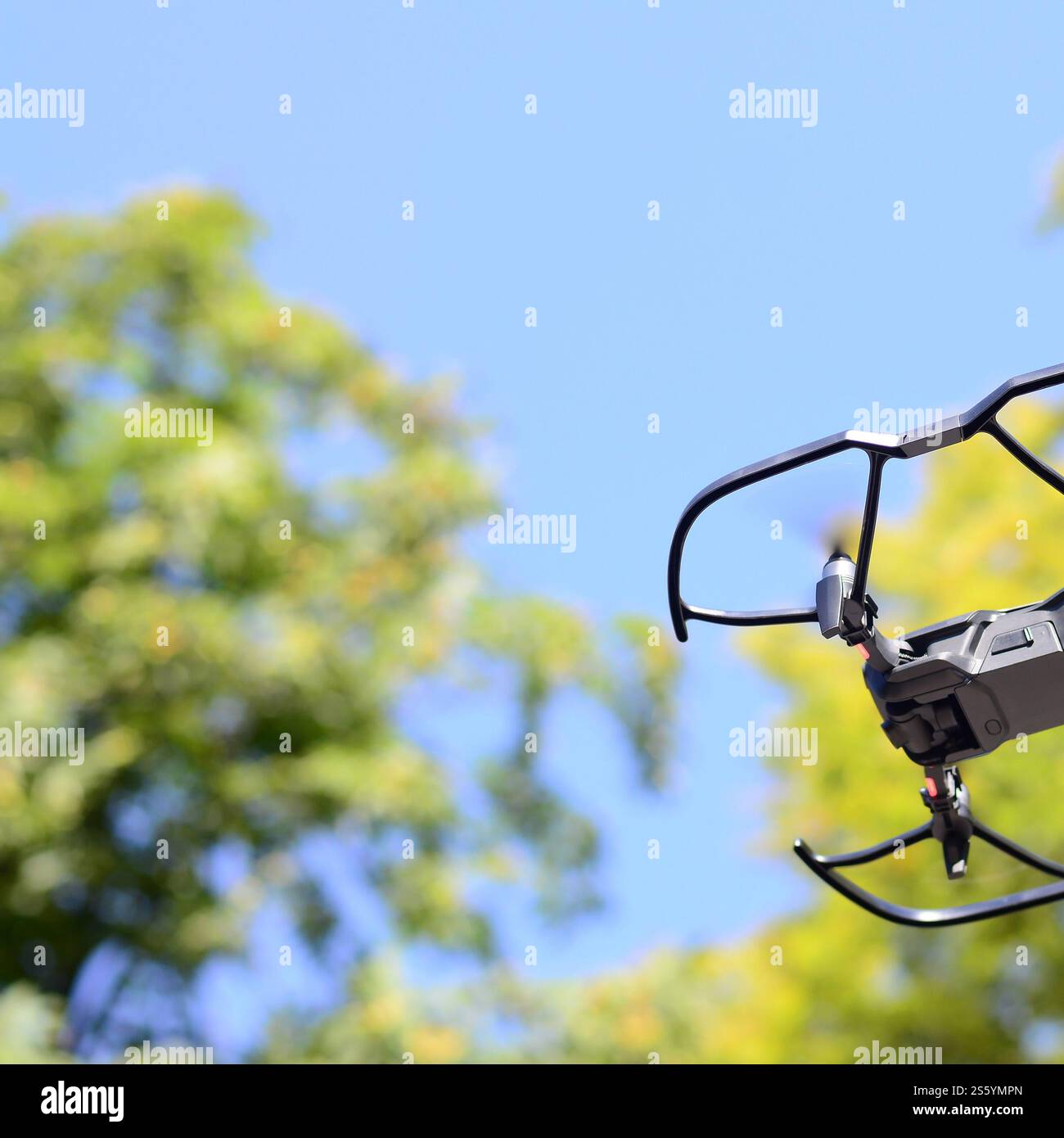 Drone con fotocamera decolla dalla terraferma e vola per scattare foto aeree al tramonto davanti agli alberi. Drone con fotocamera decollo da Foto Stock