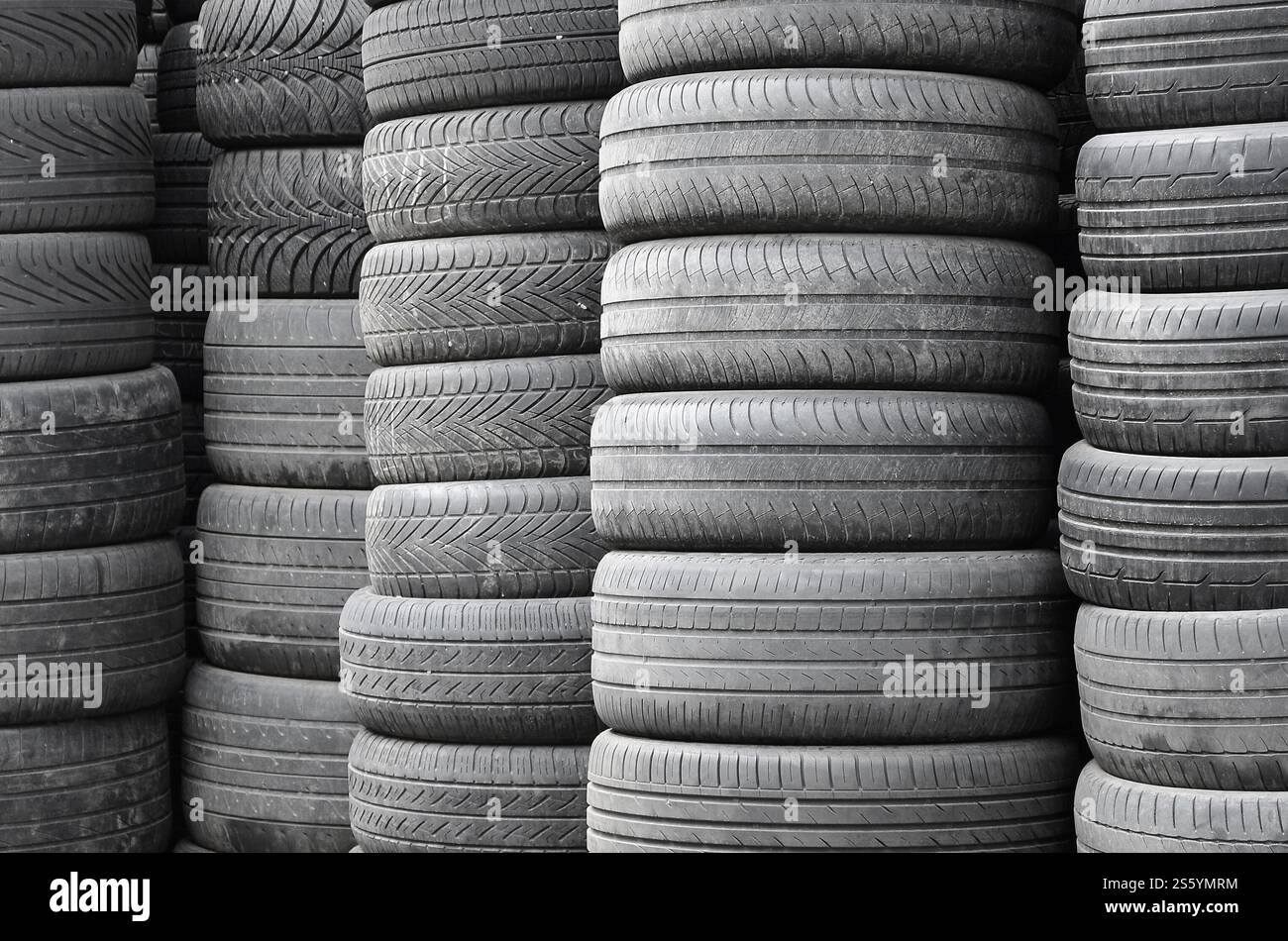 Vecchi pneumatici usati impilati con pali alti in un'officina di ricambi per auto secondarie da vicino. Vecchi pneumatici usati impilati con pali alti nelle parti di un'auto secondaria Foto Stock