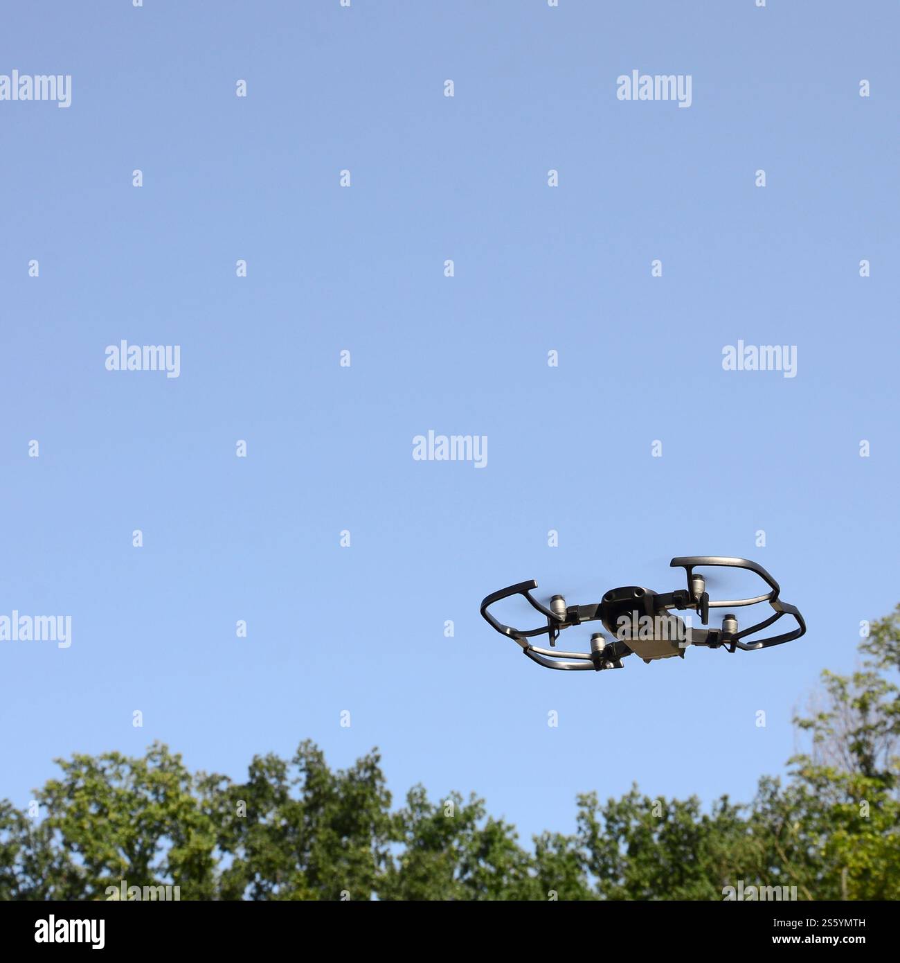 Drone con fotocamera decolla dalla terraferma e vola per scattare foto aeree al tramonto davanti agli alberi. Drone con fotocamera decollo da Foto Stock