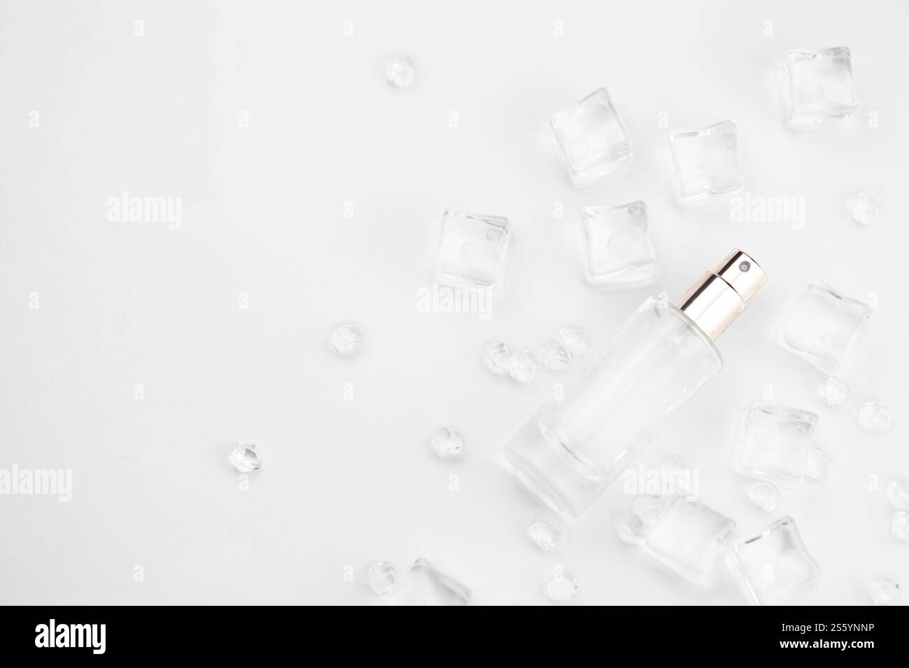Bottiglia di profumo femminile, fotografia oggettiva della bottiglia di profumo in cubetti di ghiaccio e acqua. vista dall'alto. foto del prodotto, concetto di freschezza e aroma. Foto Stock