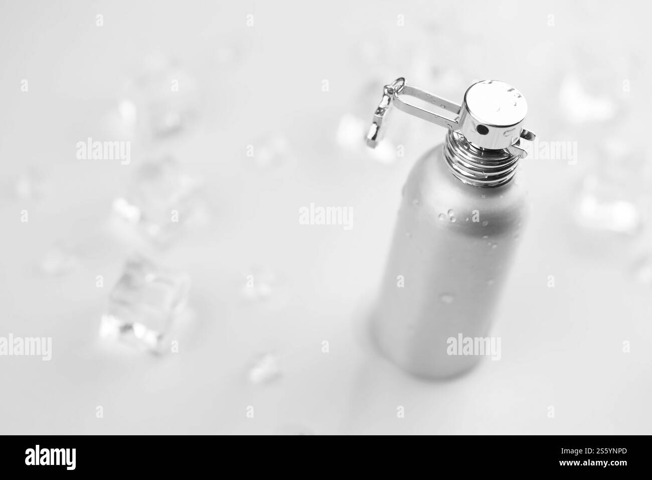 Bottiglia argentata di profumo femminile, Fotografia obiettivo di bottiglia di profumo metallico in cubetti di ghiaccio e acqua su tavola bianca. Vista dall'alto. Prodotto mockup Foto Stock