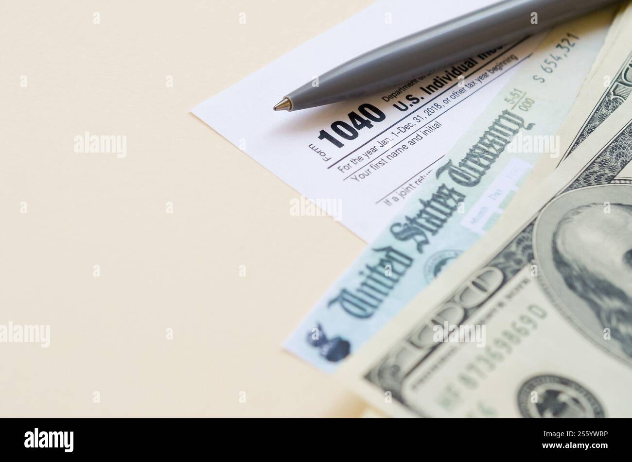 1040 modulo di dichiarazione dei redditi individuali con assegno di rimborso e banconote da cento dollari su sfondo beige. Concetto del periodo fiscale. Pianificazione finanziaria e. Foto Stock
