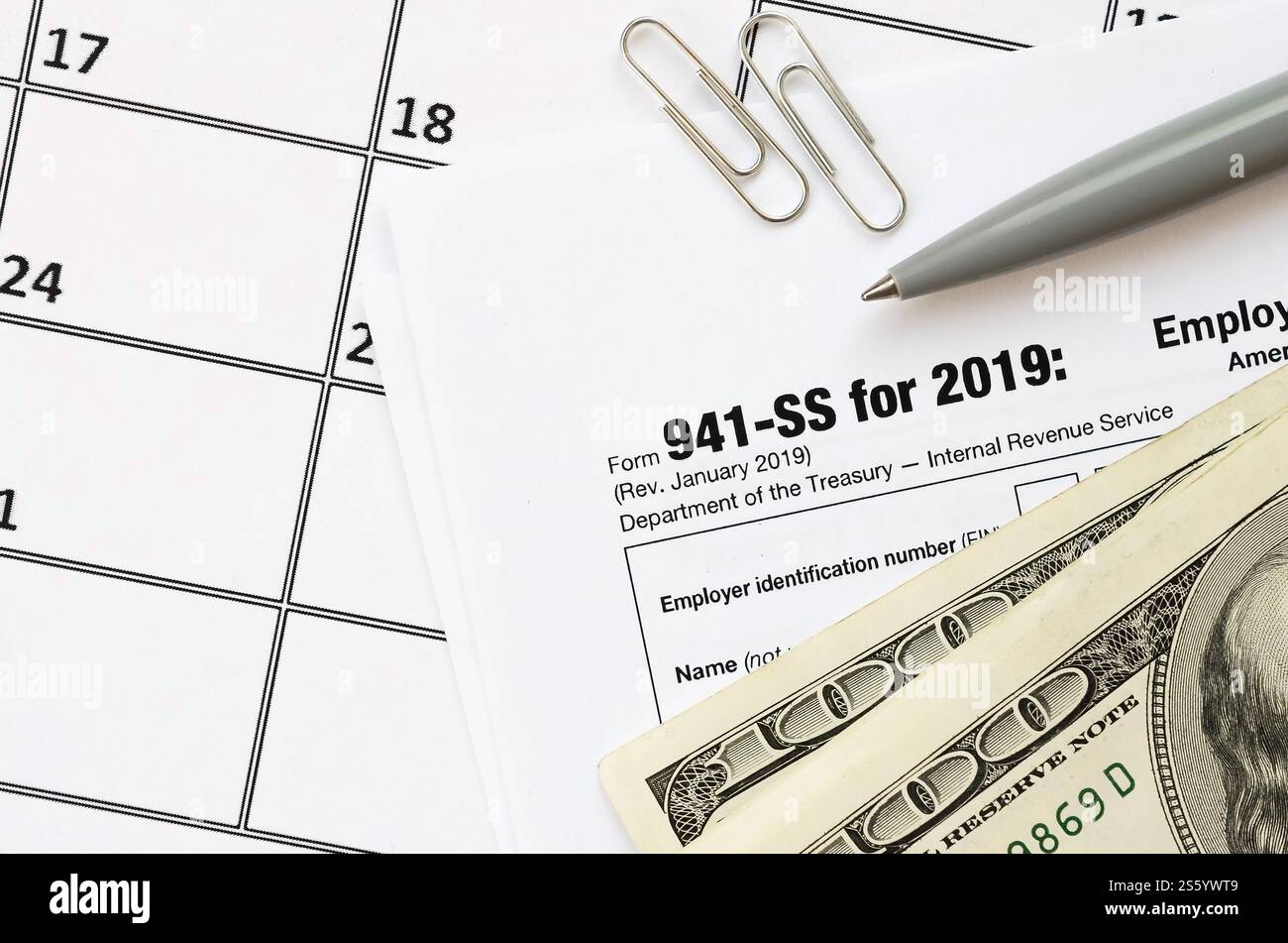 Modulo IRS 941-SS datori di lavoro dichiarazione dei redditi federale trimestrale in bianco si trova con penna e molte banconote da cento dollari sulla pagina del calendario. Concetto del periodo fiscale. Copia Foto Stock