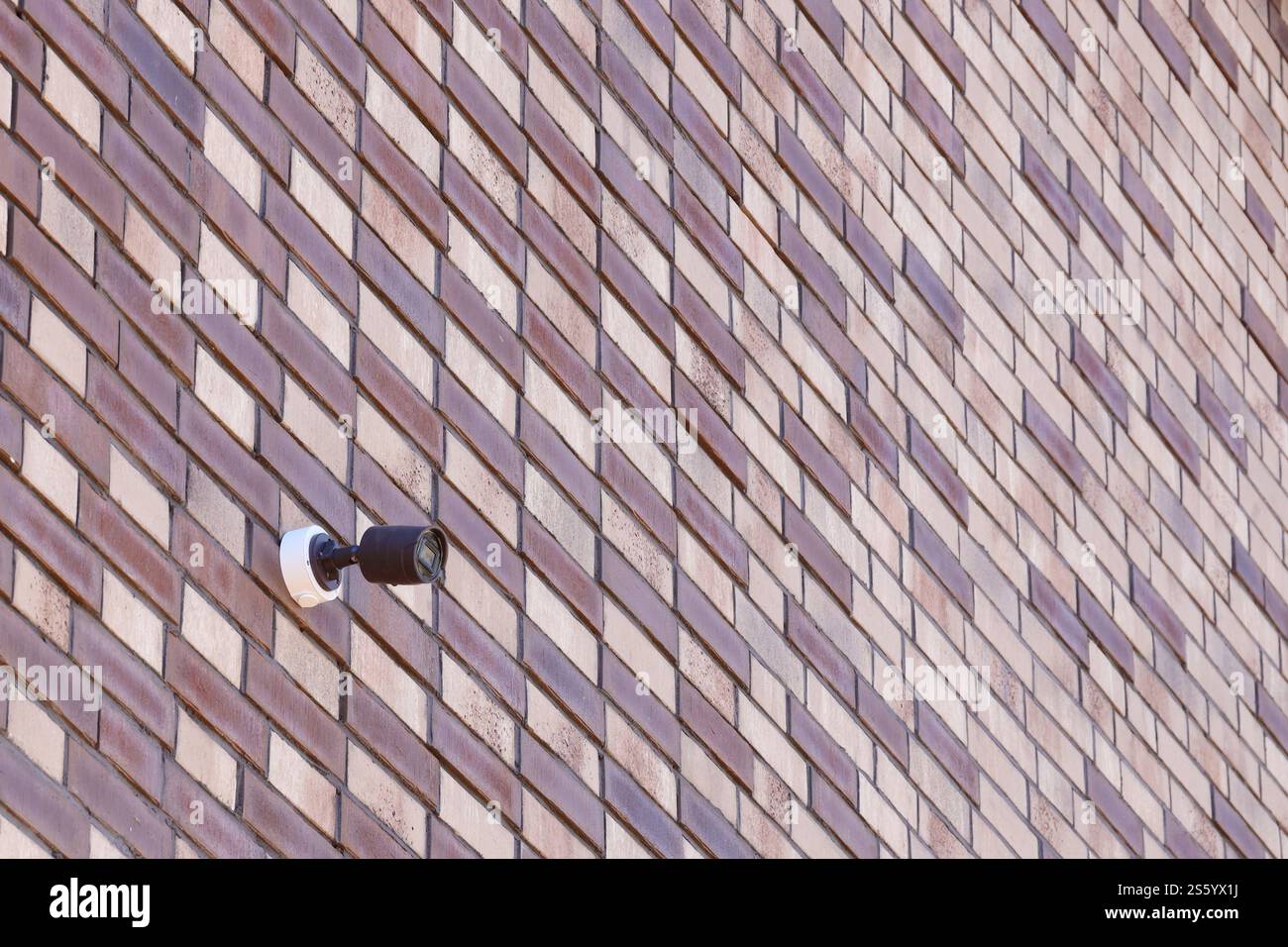 Telecamera di sicurezza CCTV wireless nera per la sorveglianza dell'area posizionata su una parete di mattoni. Le telecamere di sorveglianza sono tecnologie moderne per prevenire i ladri e. Foto Stock