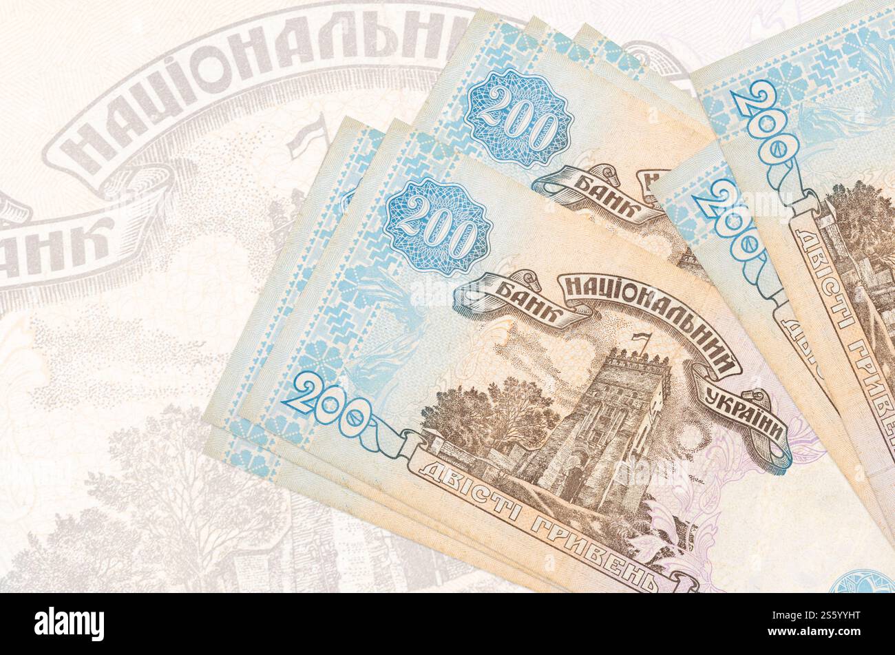 200 banconote ucraine in hryvnias si trovano in una pila sullo sfondo di una grande banconota semi-trasparente. Presentazione astratta della moneta nazionale. Affari Foto Stock