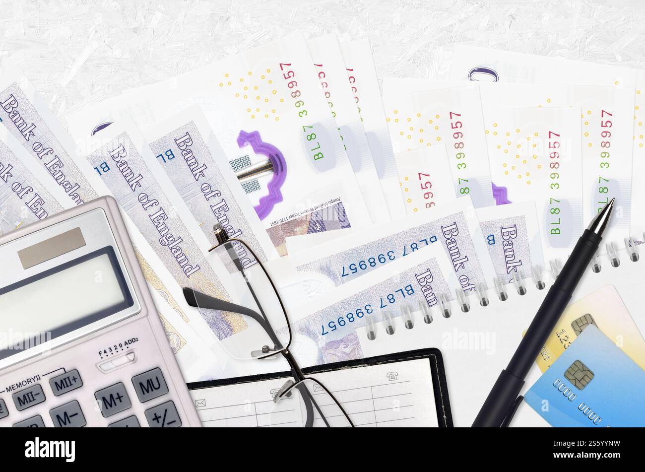 Banconote da 20 sterline britanniche e calcolatrice con occhiali e penna. Concetto di stagione del pagamento delle imposte o soluzioni di investimento. Pianificazione finanziaria o contabile Foto Stock