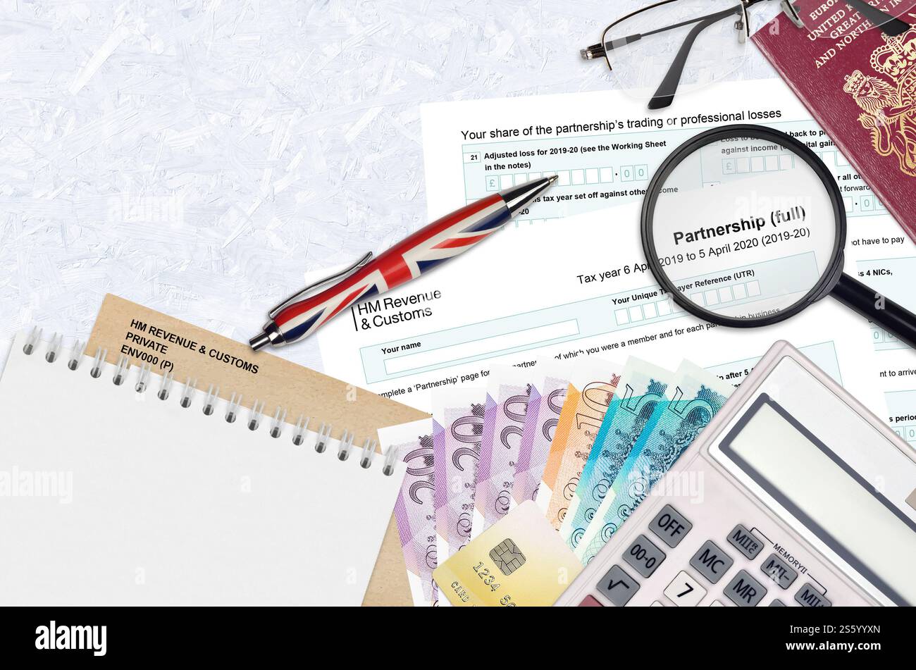 Modulo fiscale inglese sa104 Partnership di HM revenue and Customs si trova sul tavolo con gli articoli per ufficio. Documentazione HMRC e processo di pagamento delle tasse in United Foto Stock