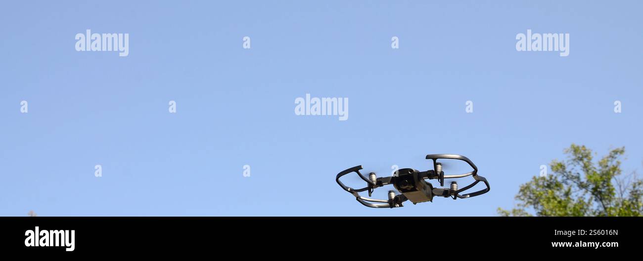 Drone con fotocamera decolla dalla terraferma e vola per scattare foto aeree al tramonto davanti agli alberi. Drone con fotocamera decollo da Foto Stock