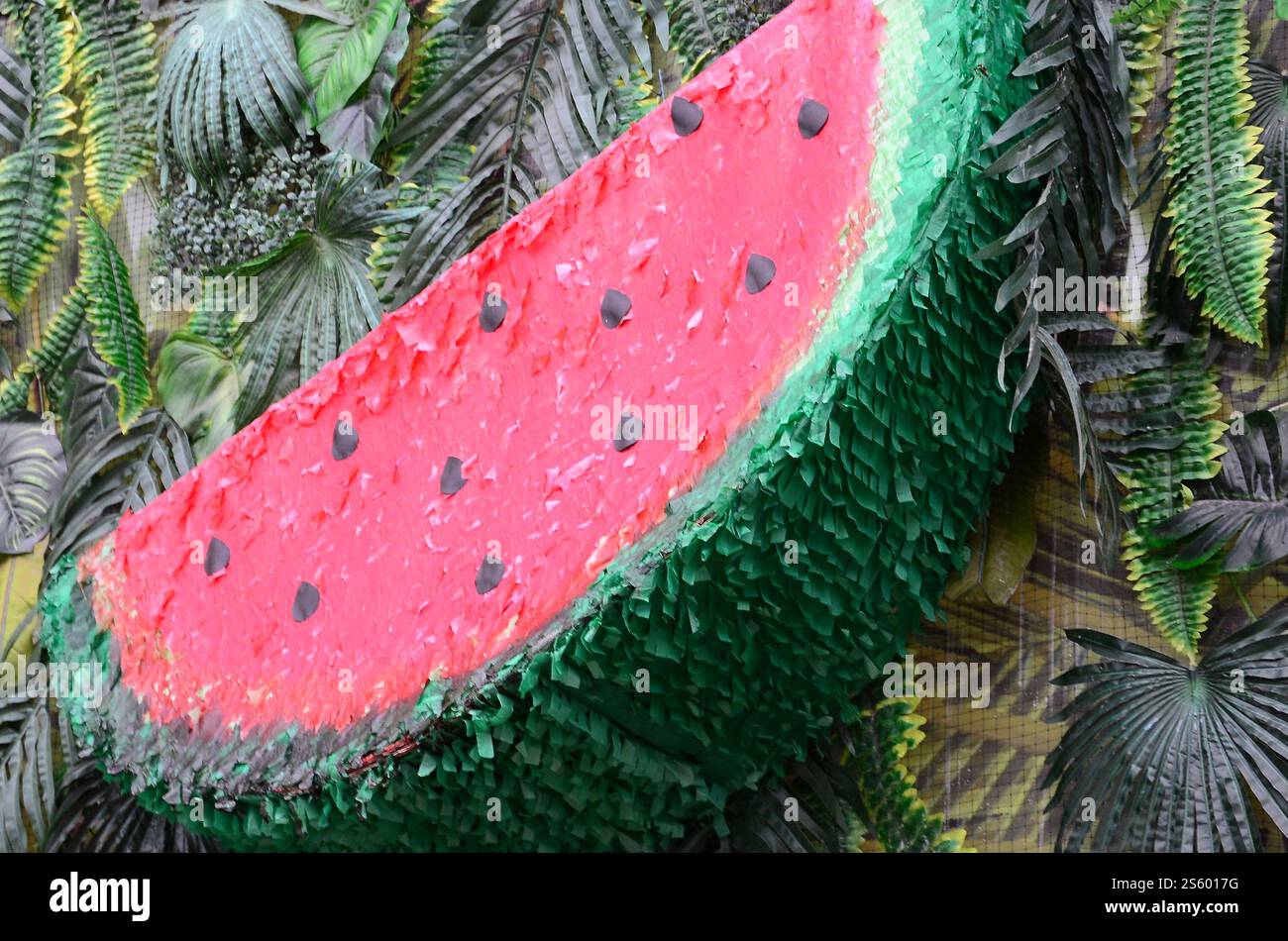 Motivo tropicale con foglie di giungla e fondo floreale di frutta anguria. Fetta di anguria di plastica con foglia di palma. Motivo tropicale con giungla Foto Stock