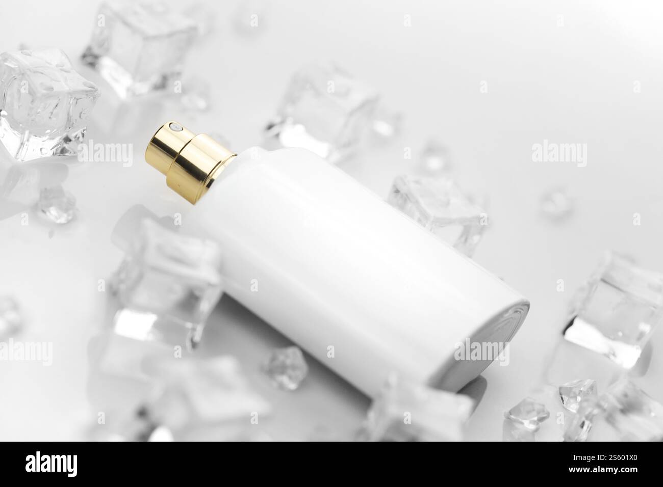 Bottiglia bianca di profumo femminile, fotografia obiettiva di bottiglia di profumo in cubetti di ghiaccio e acqua su tavola bianca. Vista dall'alto. Foto prodotto mockup, Foto Stock