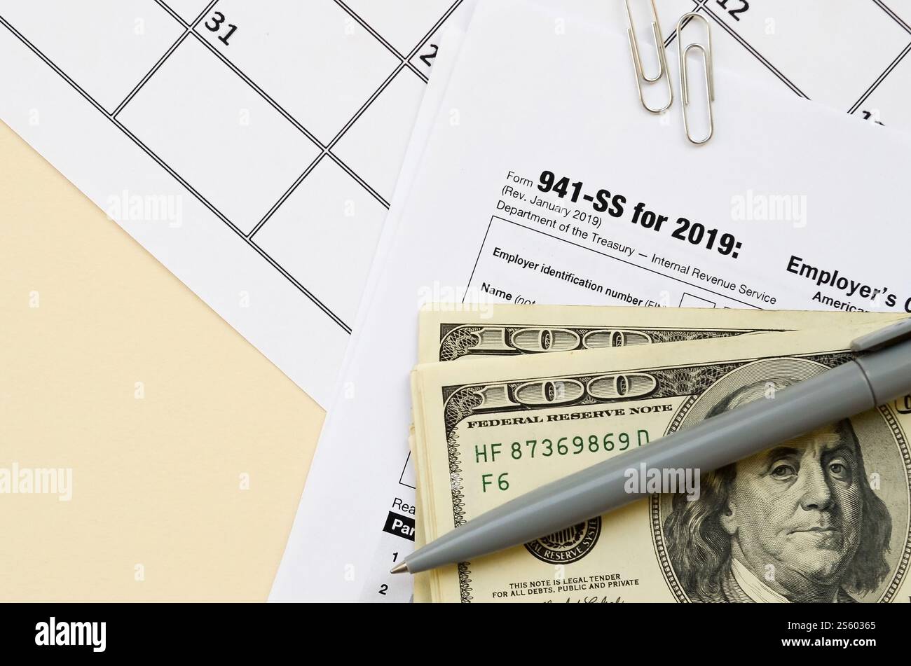 Modulo IRS 941-SS datori di lavoro dichiarazione dei redditi federale trimestrale in bianco si trova con penna e molte banconote da cento dollari sulla pagina del calendario. Concetto del periodo fiscale. Copia Foto Stock