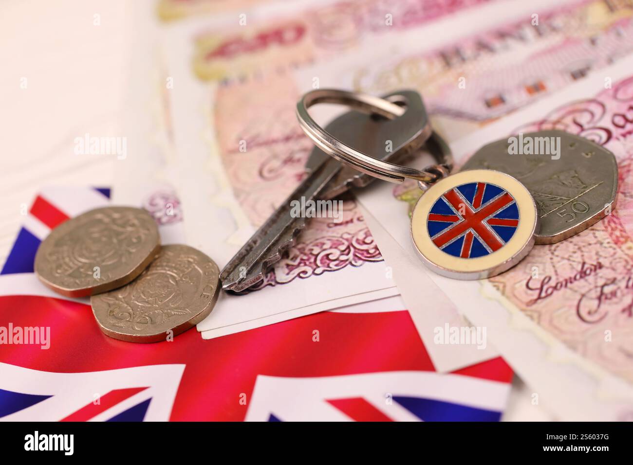 Banconote e chiavi per la casa da vicino. Grande quantità di sterline britanniche e chiave d'argento sul tavolo. Concetto di affari e immobiliare per l'Inghilterra. Foto Stock