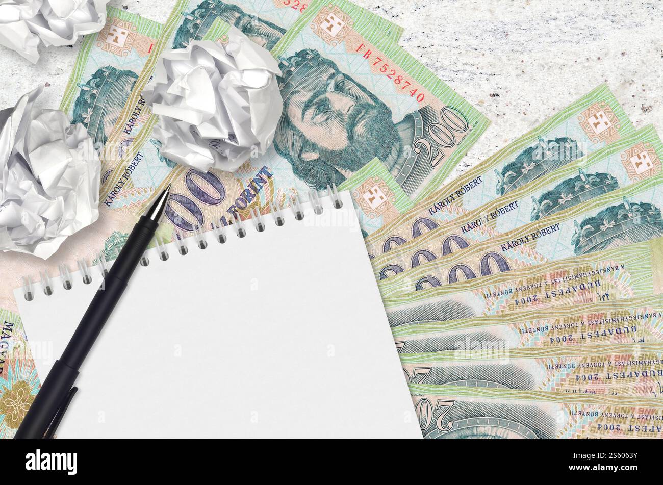 200 banconote ungheresi e palle di carta increspata con blocco note. Idee cattive o meno di concetto di ispirazione. Alla ricerca di idee per l'investimento. 200 Foto Stock
