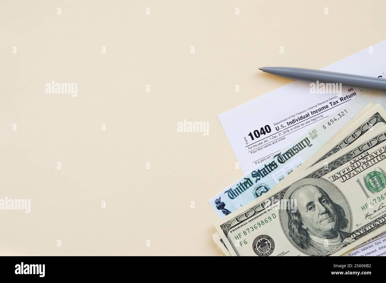 1040 modulo di dichiarazione dei redditi individuali con assegno di rimborso e banconote da cento dollari su sfondo beige. Concetto del periodo fiscale. Pianificazione finanziaria e. Foto Stock