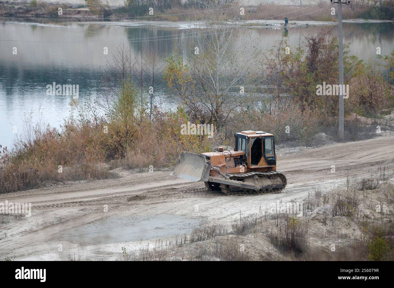 Aggregato da cava con macchinari per impieghi gravosi nel settore delle costruzioni. Escavatore pala Caterpillar con retroescavatore per la cava del cantiere. Foto Stock