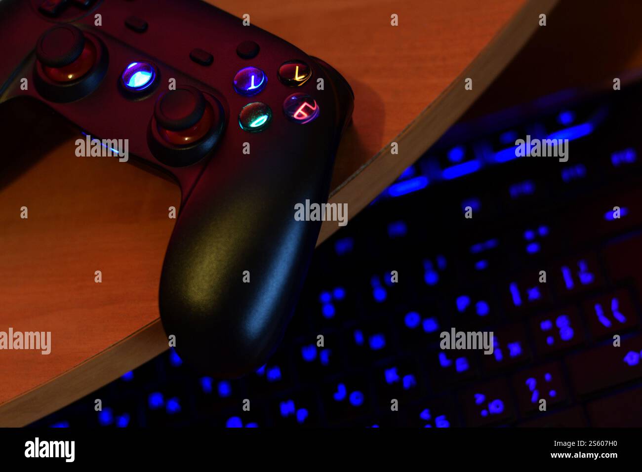 Il moderno gamepad è dotato di tastiera per pc sul tavolo in una scena da vicino scura della stanza dei giochi. Consente di giocare ai videogame insieme a Friends Concept. Gamepad moderno Foto Stock