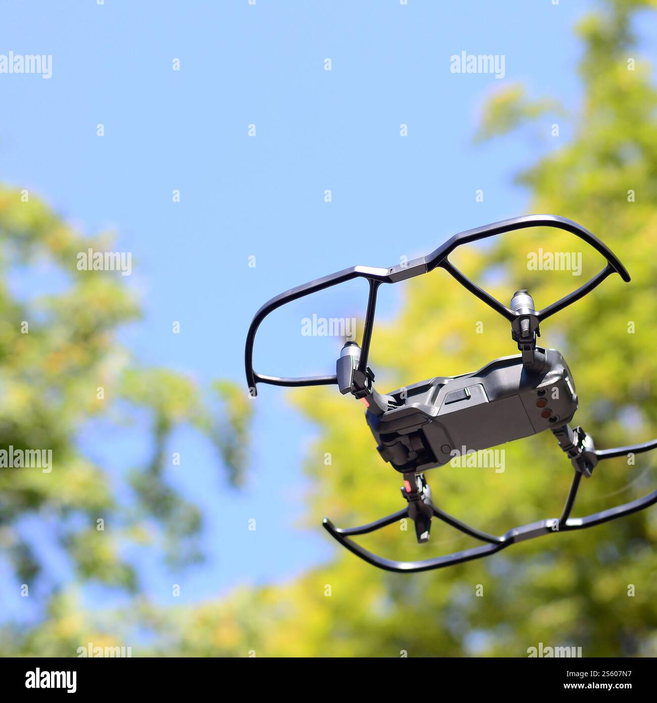 Drone con fotocamera decolla dalla terraferma e vola per scattare foto aeree al tramonto davanti agli alberi. Drone con fotocamera decollo da Foto Stock