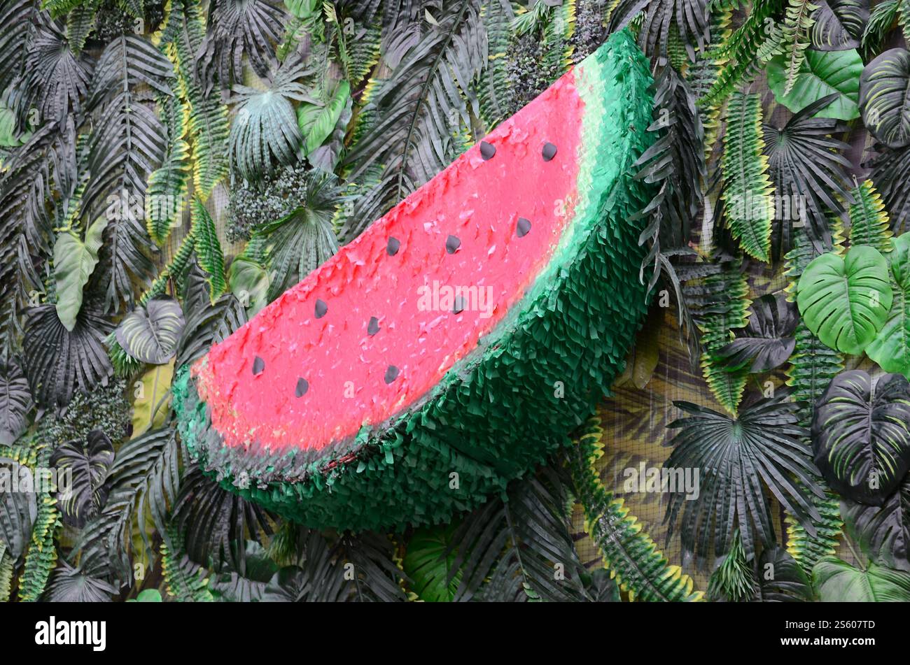 Motivo tropicale con foglie di giungla e fondo floreale di frutta anguria. Fetta di anguria di plastica con foglia di palma. Motivo tropicale con giungla Foto Stock