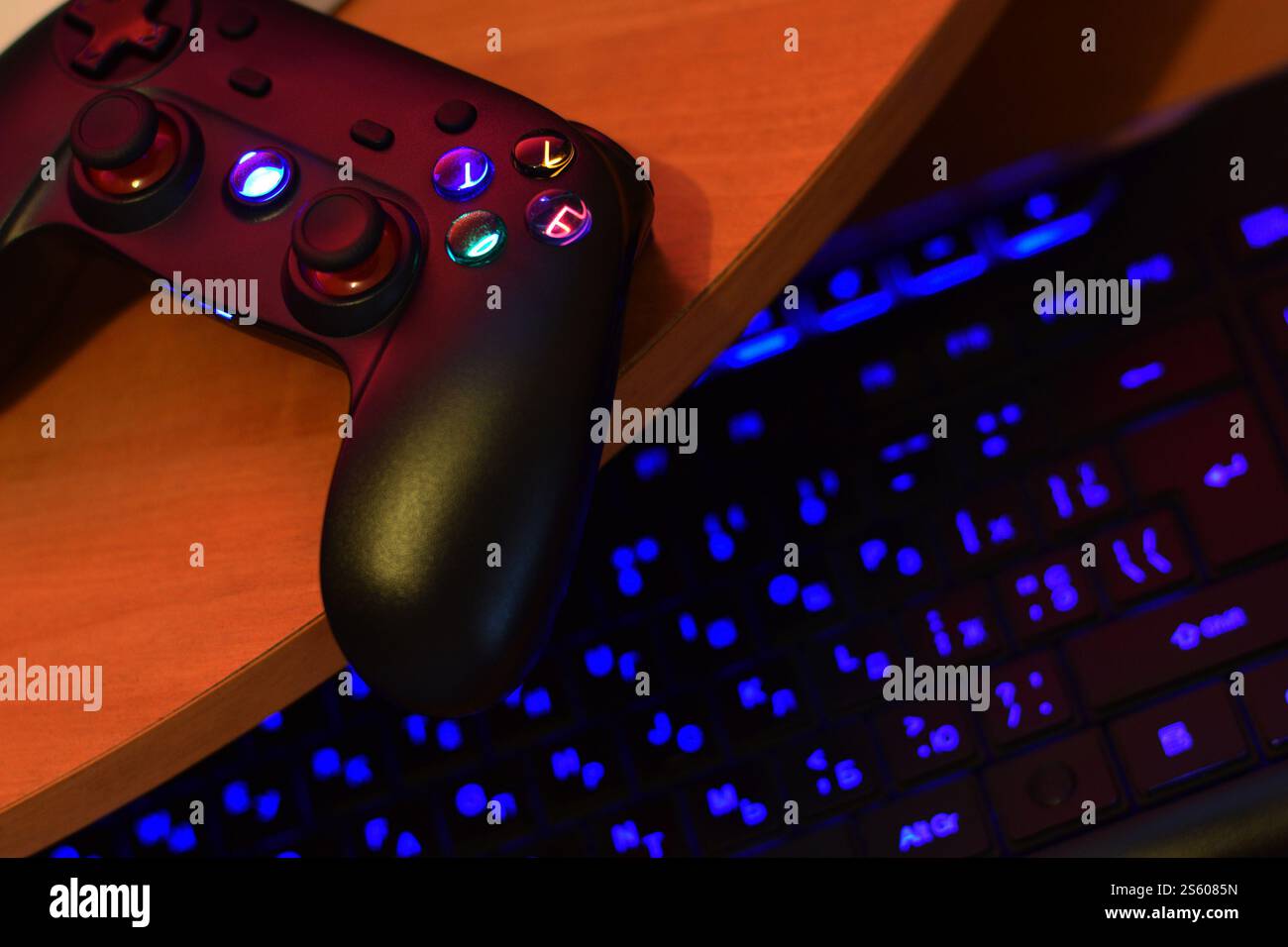 Il moderno gamepad è dotato di tastiera per pc sul tavolo in una scena da vicino scura della stanza dei giochi. Concetto di gioco di squadra cooperativo. Il moderno gamepad è dotato di tastiera per pc Foto Stock