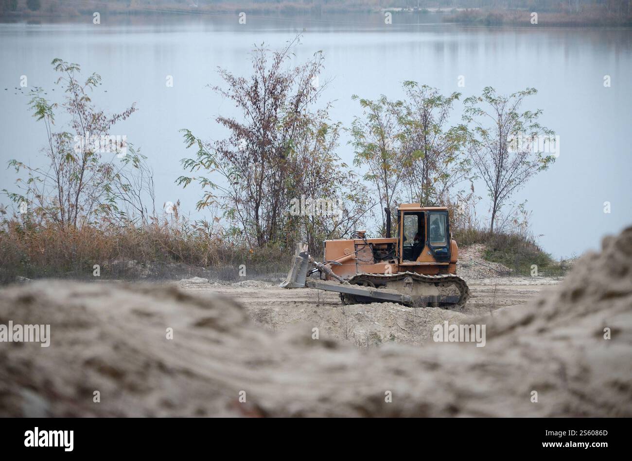 Aggregato da cava con macchinari per impieghi gravosi nel settore delle costruzioni. Escavatore pala Caterpillar con retroescavatore per la cava del cantiere. Foto Stock