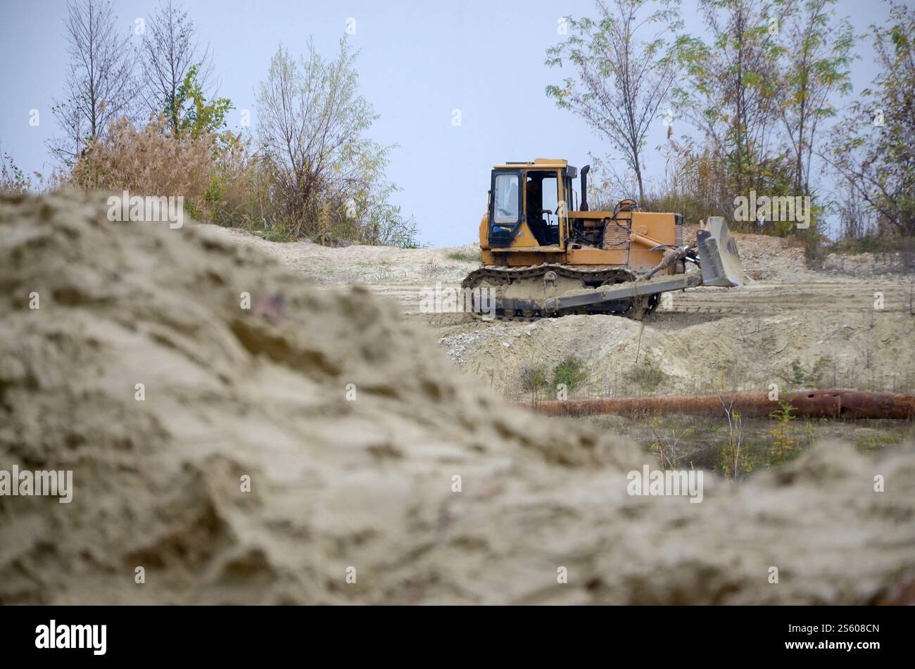 Aggregato da cava con macchinari per impieghi gravosi nel settore delle costruzioni. Escavatore pala Caterpillar con retroescavatore per la cava del cantiere. Foto Stock