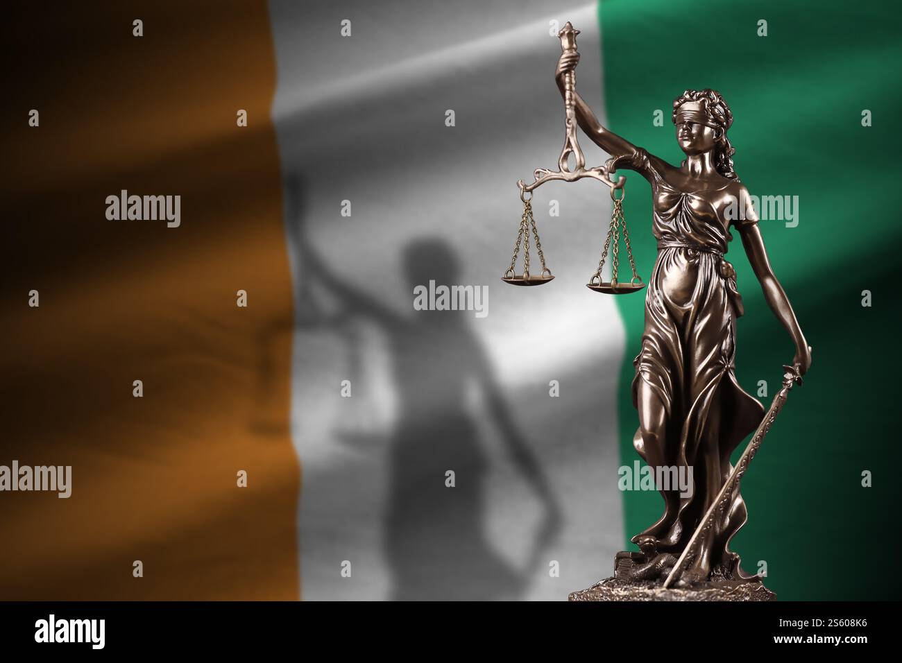 Bandiera della Costa d'Avorio con statua della giustizia e scale giudiziarie in camera buia. Concetto di giudizio e punizione, contesto per gli argomenti della giuria. Avorio Foto Stock