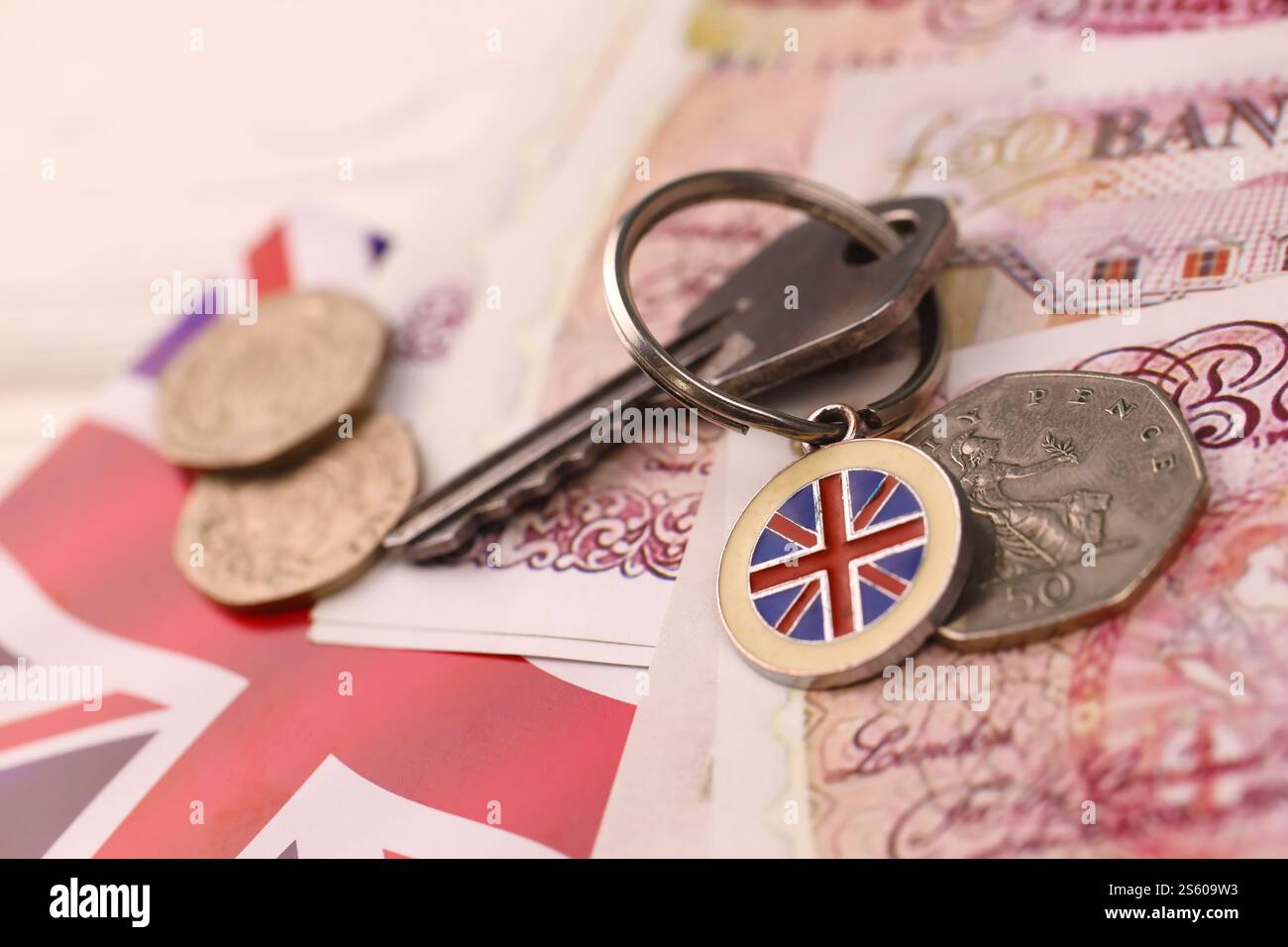 Banconote e chiavi per la casa da vicino. Grande quantità di sterline britanniche e chiave d'argento sul tavolo. Concetto di affari e immobiliare per l'Inghilterra. Foto Stock