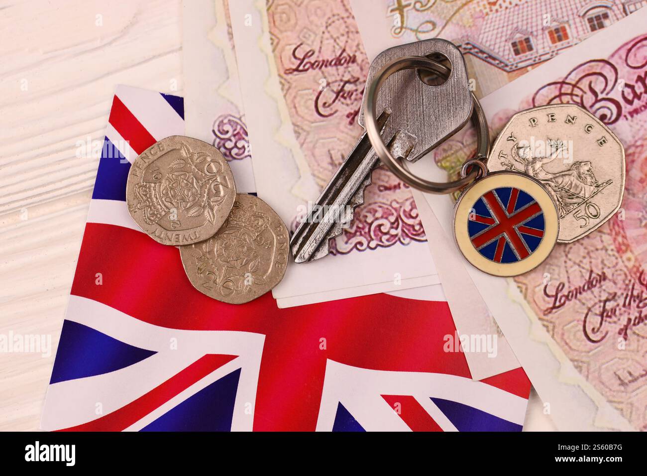 Banconote e chiavi per la casa da vicino. Grande quantità di sterline britanniche e chiave d'argento sul tavolo. Concetto di affari e immobiliare per l'Inghilterra. Foto Stock