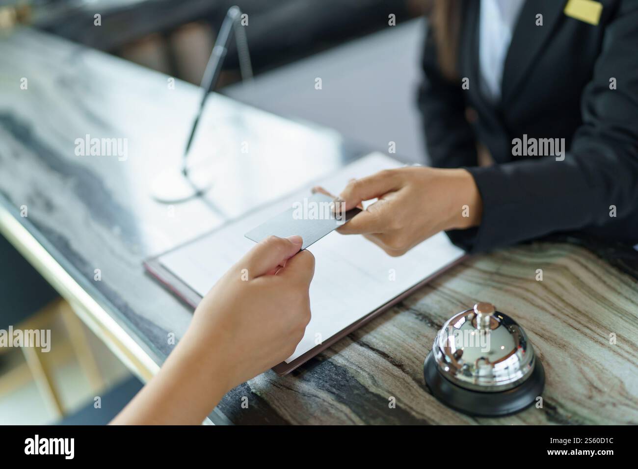 La receptionist dell'hotel in uniforme, il concierge, dà la chiave che effettua il check-in al banco dell'hotel nella lobby, il personale cordiale e accogliente al ricevimento dell'hotel Foto Stock