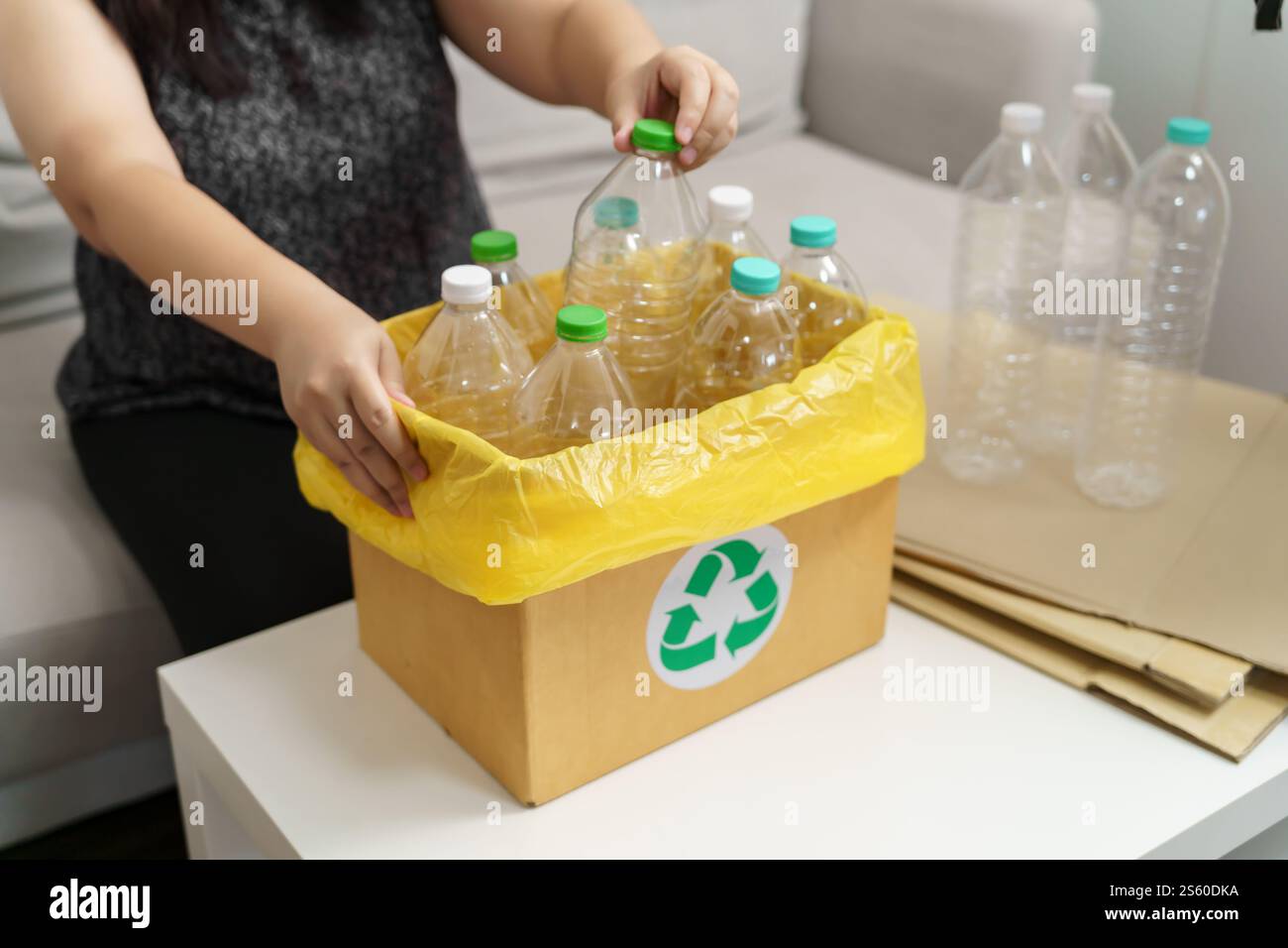 Casa ricicla donna eco-verde zero concept che lancia bottiglie di plastica vuote in un cestino con sacchetti per rifiuti gialli a casa Foto Stock
