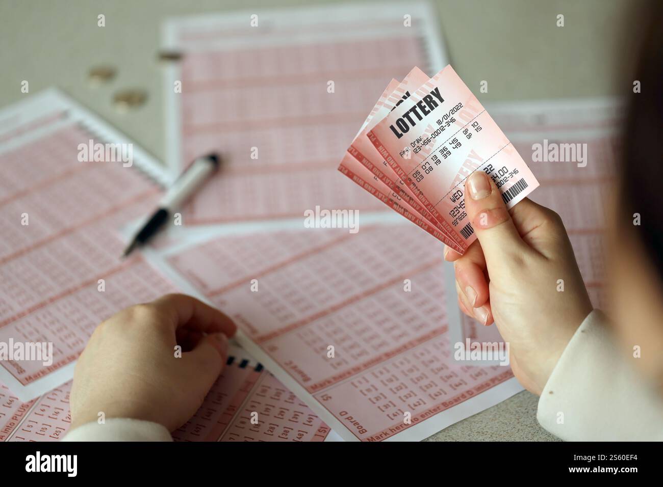 Compilare un biglietto della lotteria. Una giovane donna tiene il biglietto della lotteria con una fila completa di numeri sullo sfondo dei fogli bianchi della lotteria. Gioco d'azzardo Foto Stock