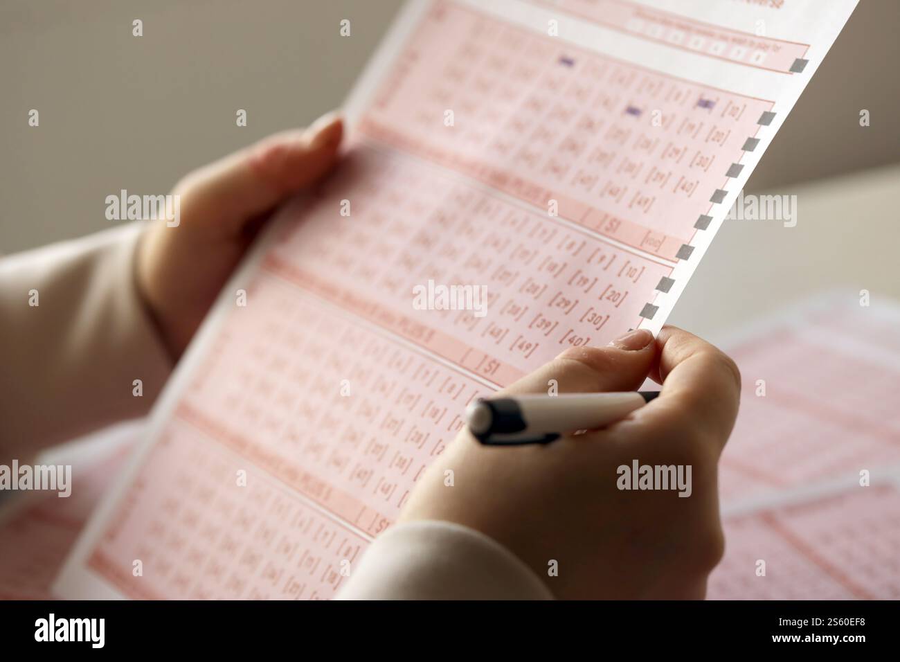 Compilare un biglietto della lotteria. Una giovane donna gioca alla lotteria e sogna di vincere il jackpot. Concetto di gioco d'azzardo. Compilare un biglietto della lotteria. A. Foto Stock