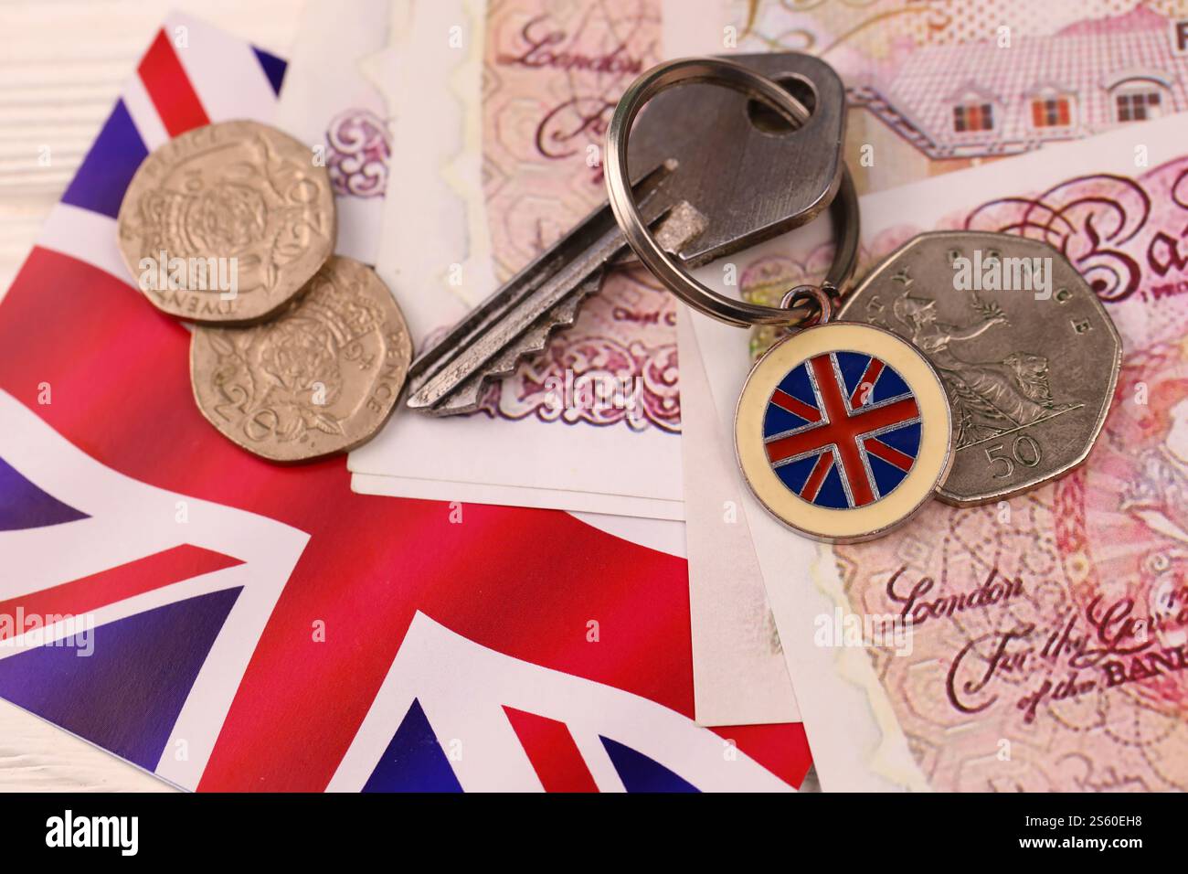 Banconote e chiavi per la casa da vicino. Grande quantità di sterline britanniche e chiave d'argento sul tavolo. Concetto di affari e immobiliare per l'Inghilterra. Foto Stock
