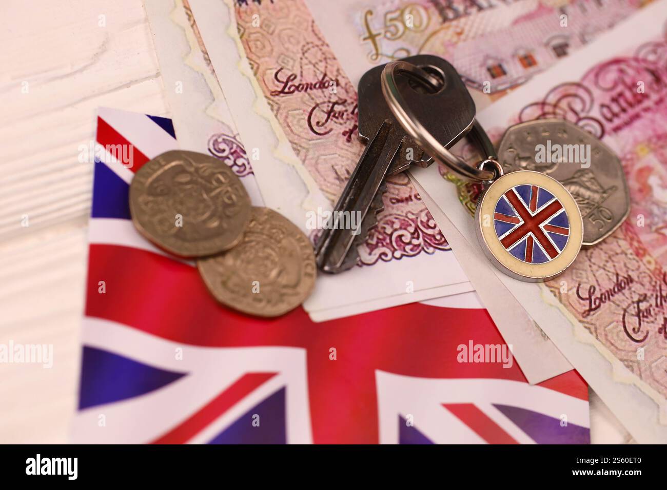 Banconote e chiavi per la casa da vicino. Grande quantità di sterline britanniche e chiave d'argento sul tavolo. Concetto di affari e immobiliare per l'Inghilterra. Foto Stock
