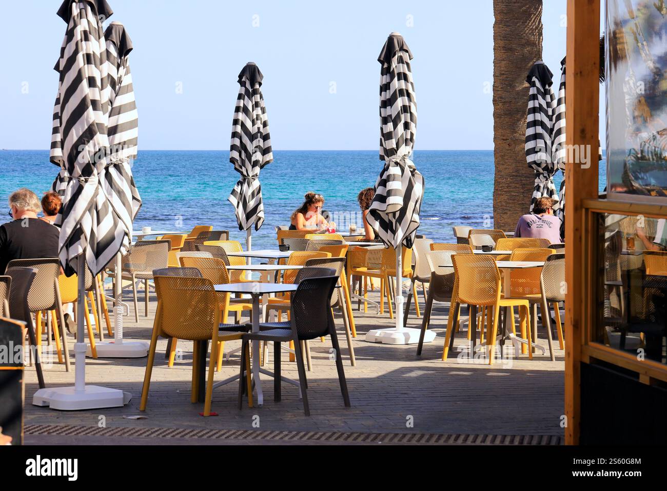 I turisti apprezzano un caffè all'aperto vicino al mare, Corralejo, Fuerteventura, Isole Canarie, Spagna, UE. Presa nel dicembre 2024 Foto Stock