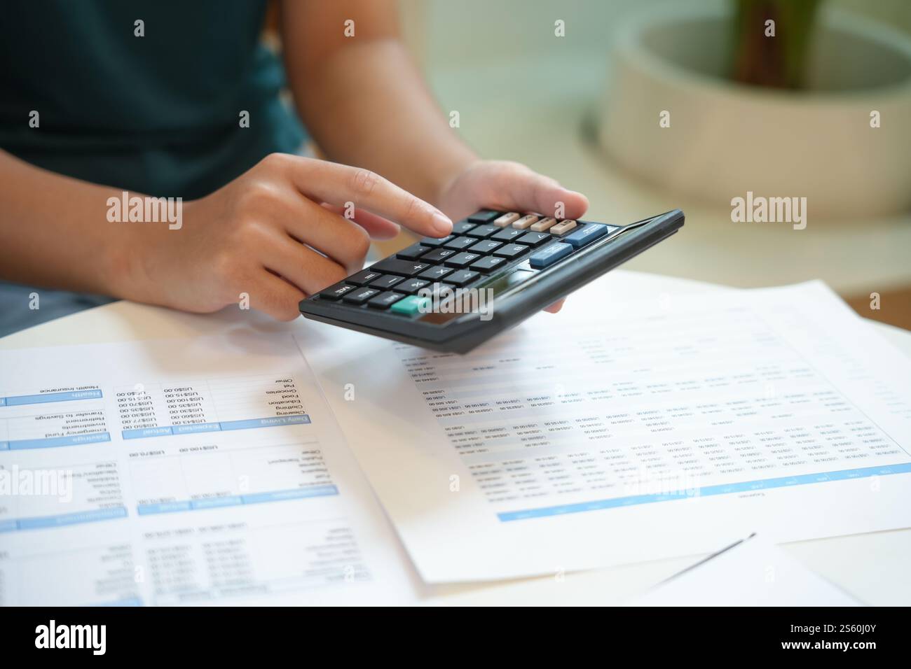 Imprenditrice contabile che analizza i grafici di investimento fattura e preme i pulsanti di calcolo sui documenti. Contabile contabile impiegato consulente bancario Foto Stock