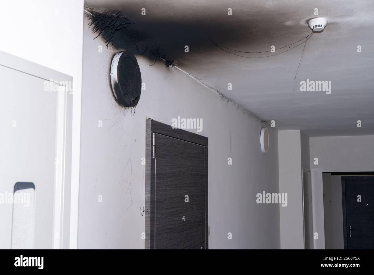 Lampada LED bruciata. Una lampada a paralume sulla parete dopo un incendio. Combustione spontanea e incendio in un edificio residenziale. Sensore di allarme antincendio interno. Porta di casa Foto Stock
