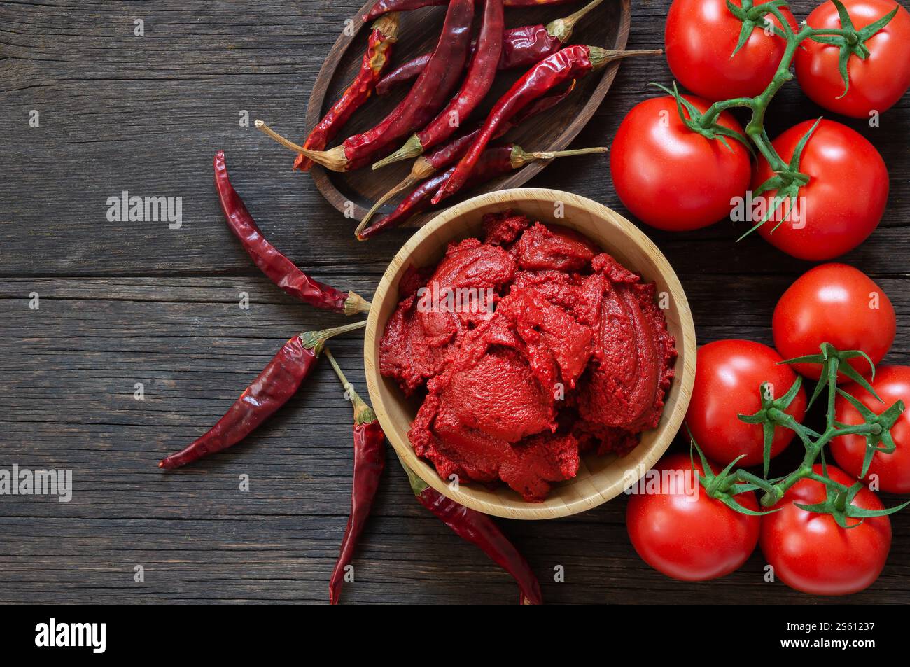 Peperoncino turco tradizionale e pasta di pomodoro nel recipiente o cucchiaio con peperoni secchi e pomodori freschi in tavola Foto Stock
