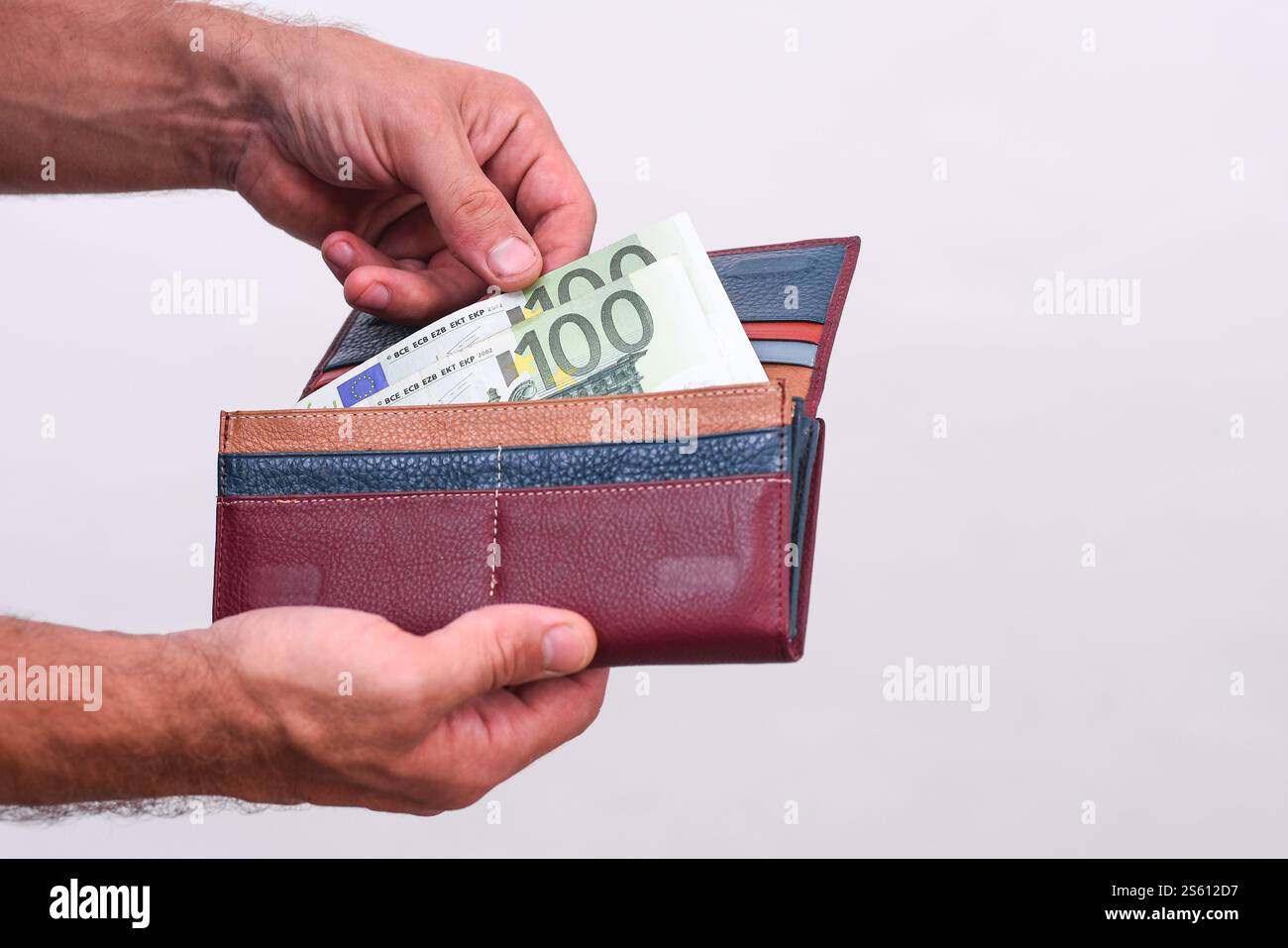 le mani degli uomini sono nel portafoglio di una banconota da 100 euro. primo piano su sfondo bianco Foto Stock