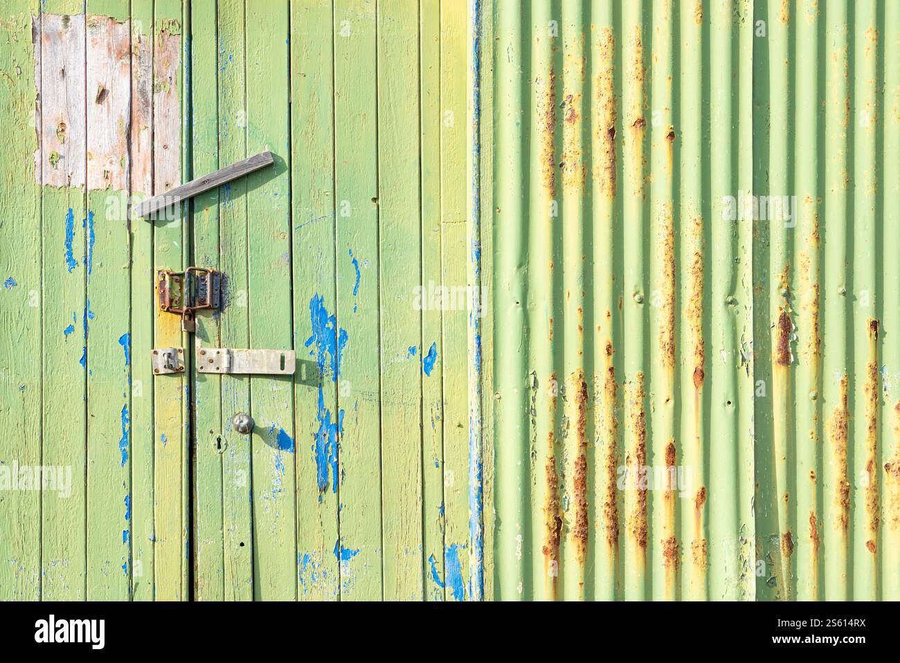 Pannelli verticali di legno verde e ferro corretto su una vecchia porta di legno con vernice casuale e varie serrature texture e vernice Foto Stock